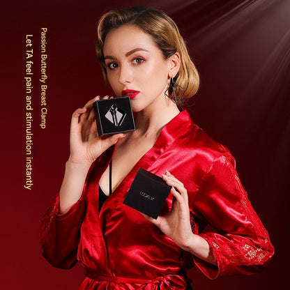Femme en robe rouge satin tenant une boîte avec pince stimulation tétons et clitoris affichée